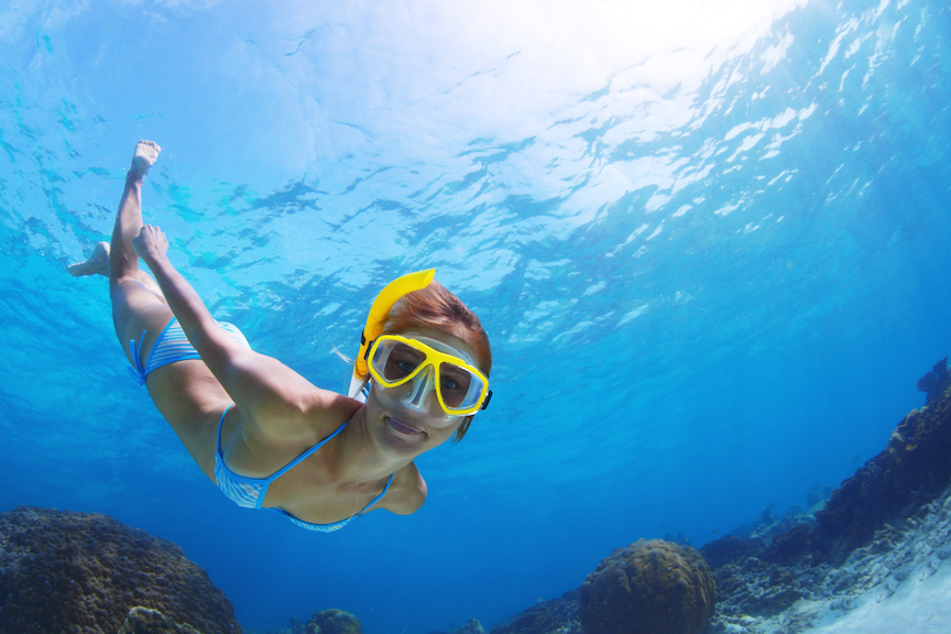 Underwater shoot of a young smiling lady snorkeling and doing skin diving in a tropical sea